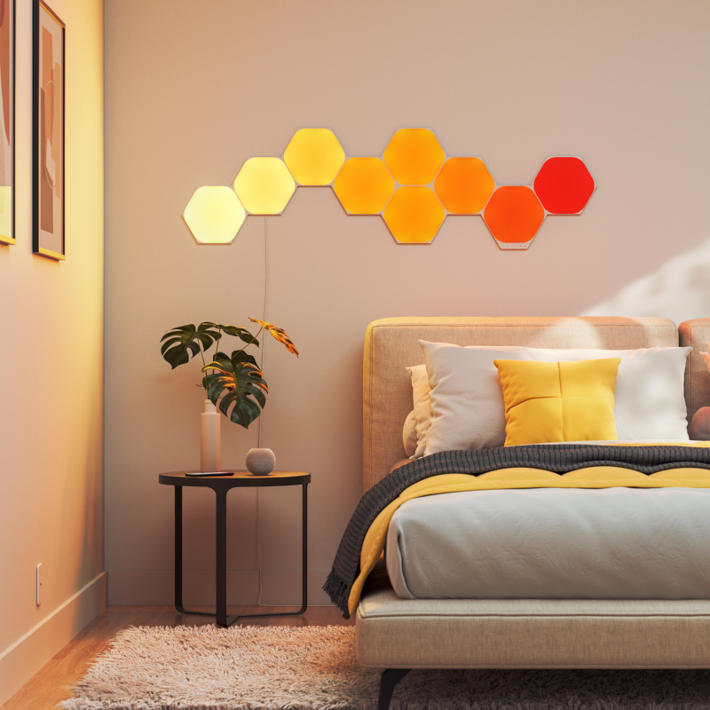 Nanoleaf Shapes Thread-enabled color-changing hexagon smart modular light panels mounted to a wall in a bedroom. Similar to Philips Hue, Lifx. HomeKit, Google Assistant, Amazon Alexa, IFTTT.
